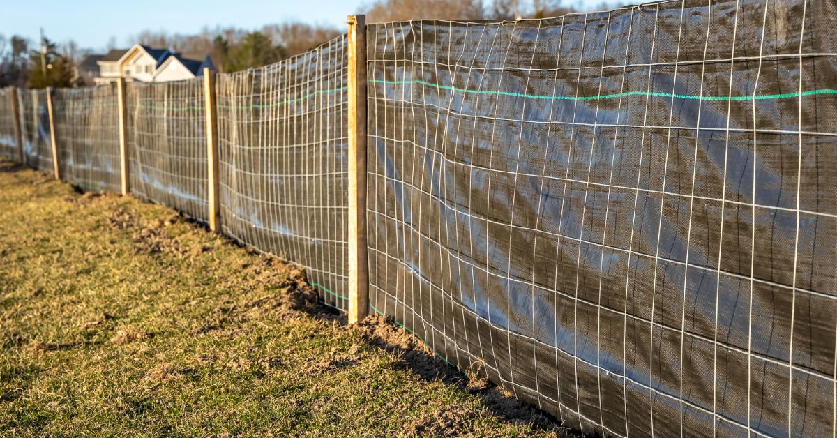 A wire fence stretching along the grass outside before construction, and wood planks keeping the wall up.