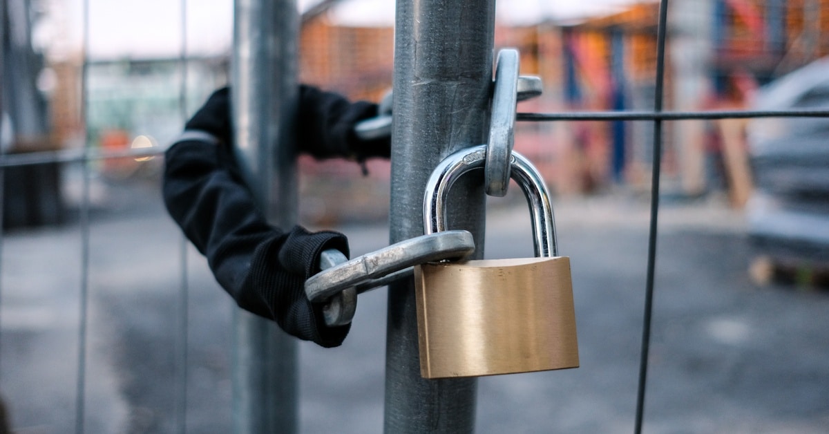 A cord wrapped around two parts of a fence and attached to a lock to keep people away from the work site.