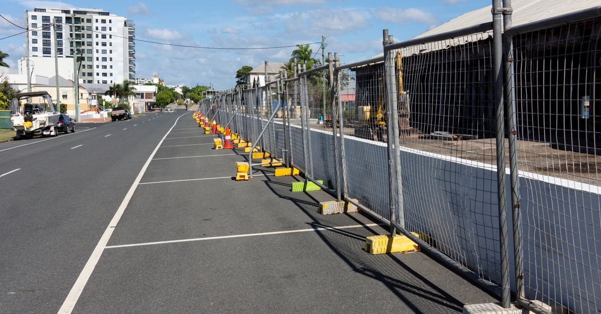 Temporary fencing protects a demolition site to keep unauthorized people out. The fence is set up along a road.